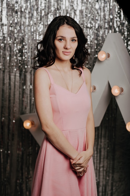 Young pretty Caucasian girl in a pink dress on a background of Christmas decor