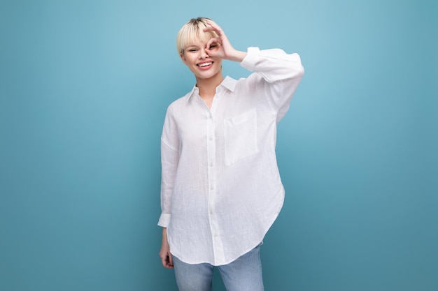 young pretty caucasian office worker woman with short blond hair is dressed in a white blouse on a blue background with copy space business concept