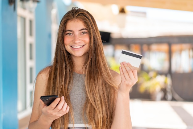 Young pretty caucasian woman buying with the mobile with a credit card