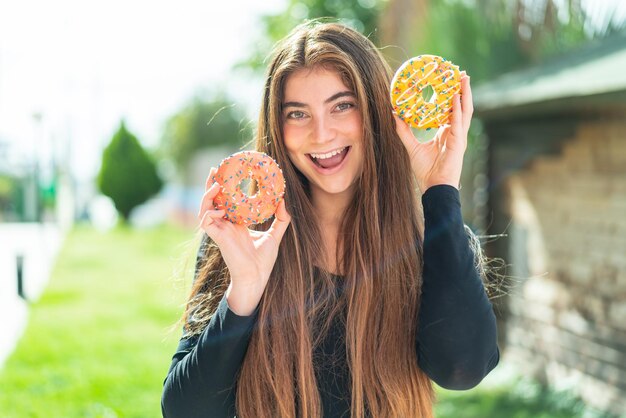 Молодая красивая белая женщина с пончиками и счастливым выражением лица.