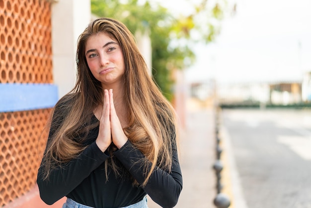 Young pretty caucasian woman keeps palm together Person asks for something