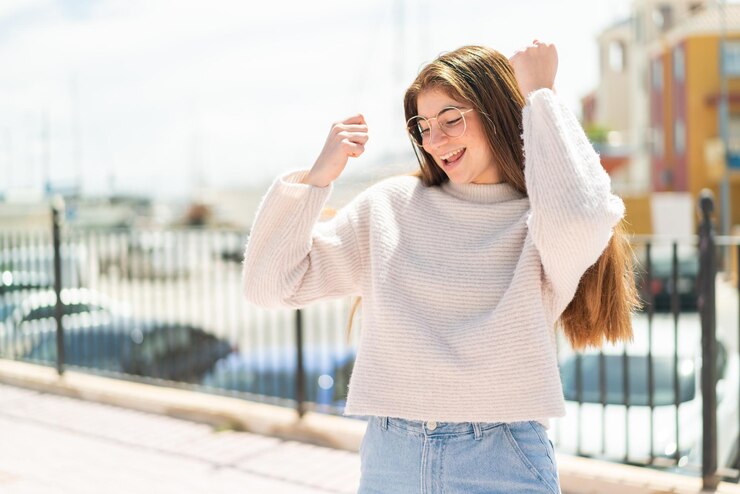 Photo 外で勝利を祝っているメガネをかぶった若い美しい白人女性