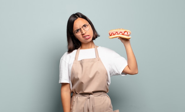 Young pretty chef woman with hot dog