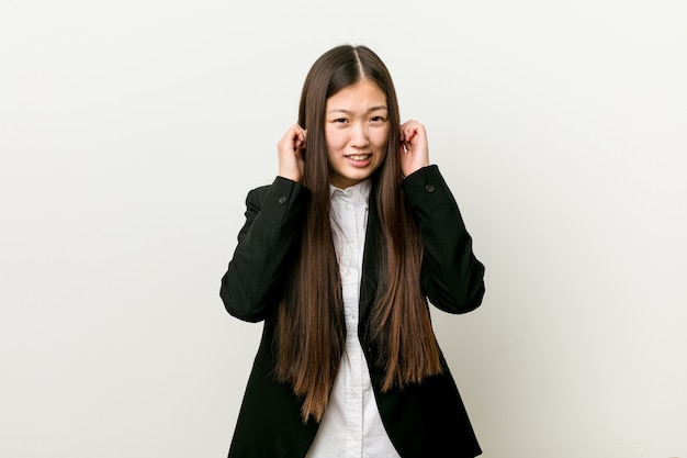 Молодые красивые китайские бизнес женщина, охватывающих уши руками.