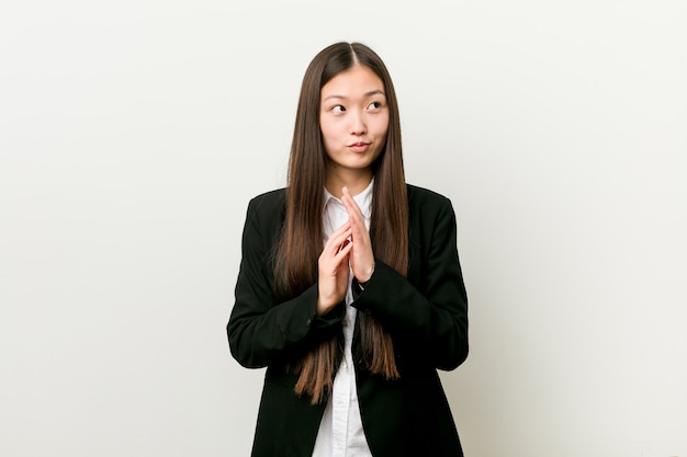 Young pretty chinese business woman making up plan in mind, setting up an idea.