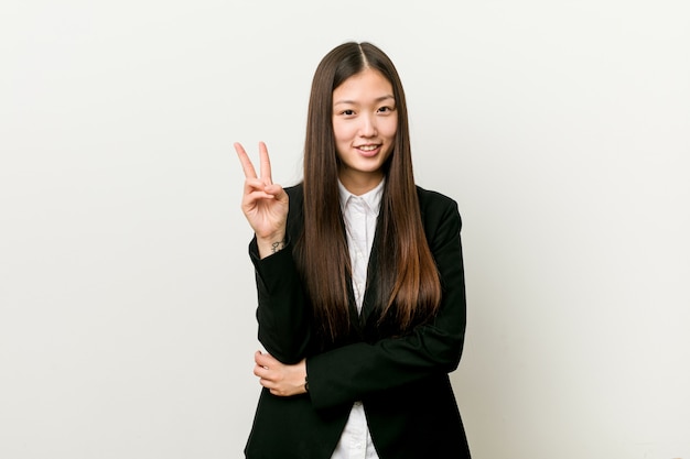 Young pretty chinese business woman showing number two with fingers.