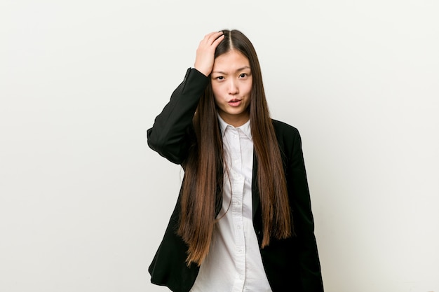 Young pretty chinese business woman tired and very sleepy keeping hand on head.