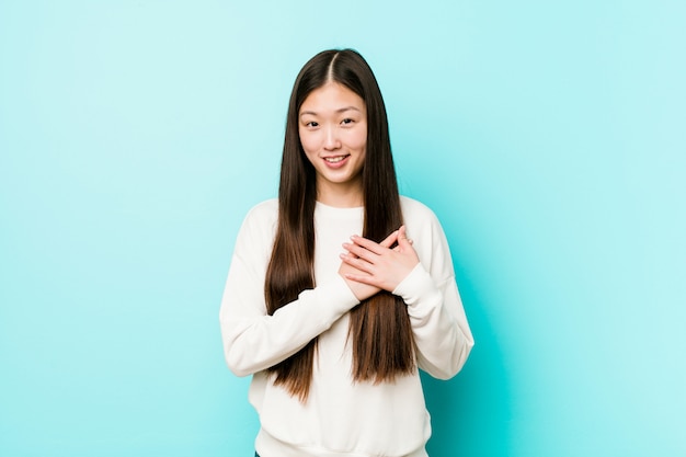 Young pretty chinese woman has friendly expression, pressing palm to chest. Love concept.