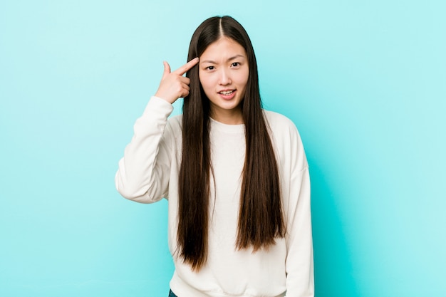 Young pretty chinese woman showing a disappointment gesture with forefinger.