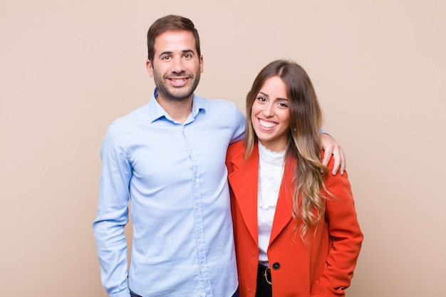 Young pretty couple against beige flat wall