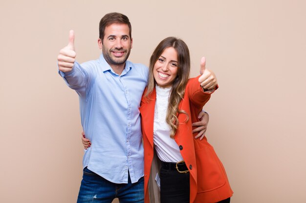 Young pretty couple against beige flat wall