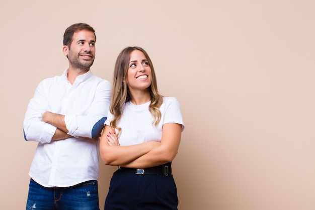 Young pretty couple against beige flat wall