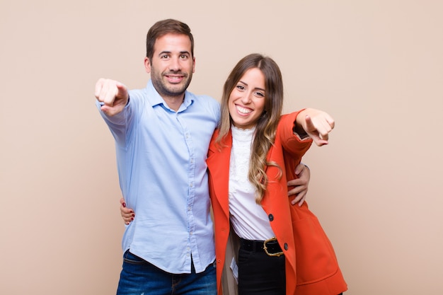 Young pretty couple against beige flat wall