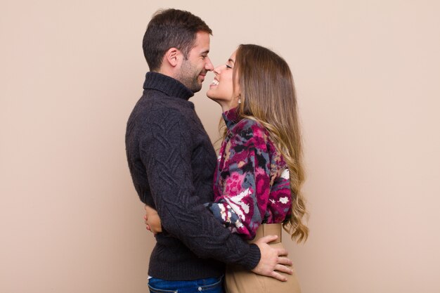 Young pretty couple against beige flat wall