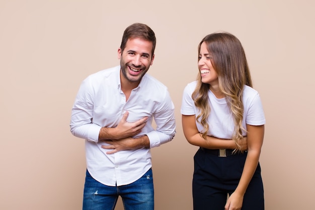 Young pretty couple against beige flat wall