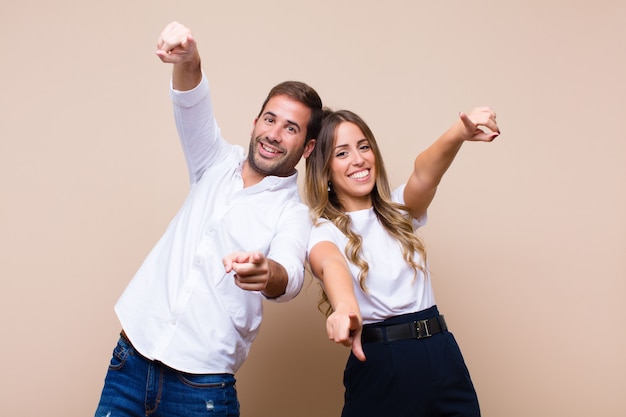 Young pretty couple against beige flat wall