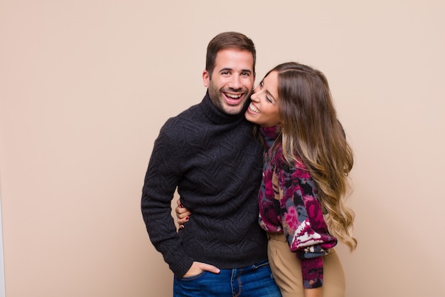 Young pretty couple against beige flat wall