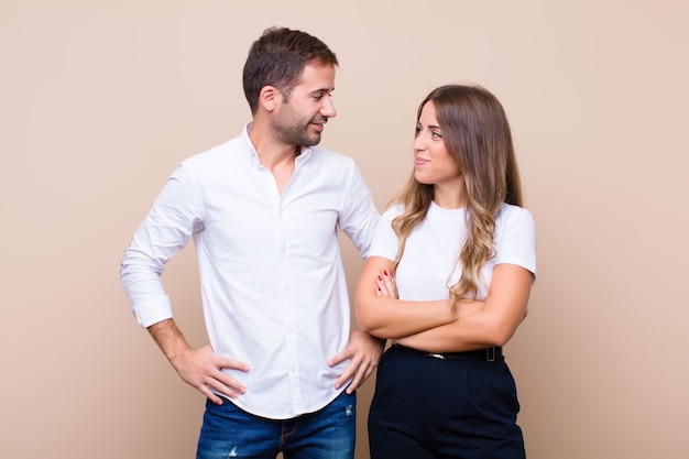 Young pretty couple against beige flat wall