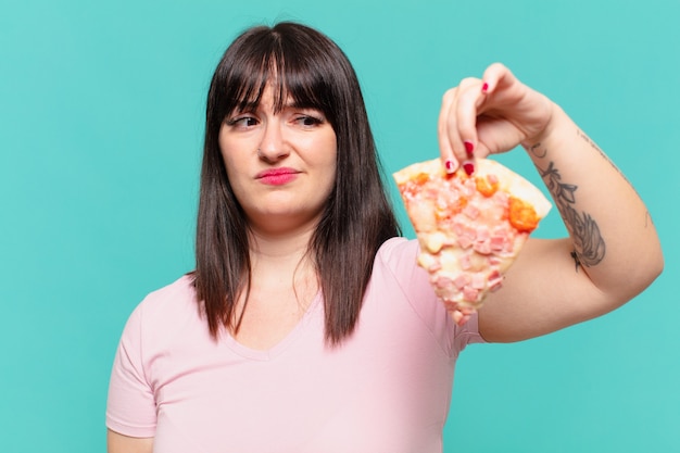 Young pretty curvy woman angry expression and holding a pizza