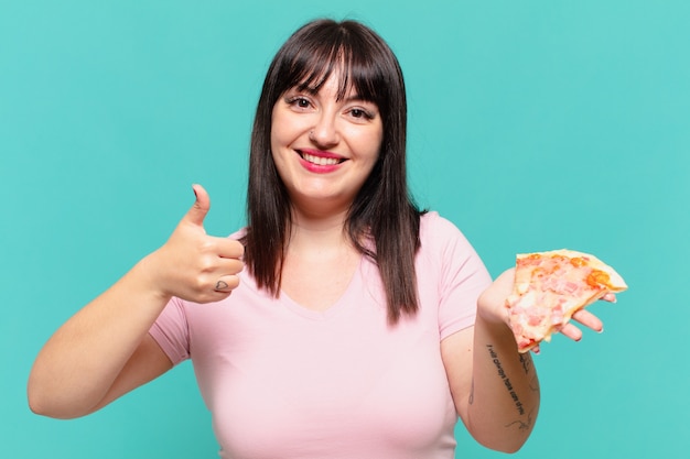 若いかなり曲がりくねった女性の幸せな表情とピザを持っています