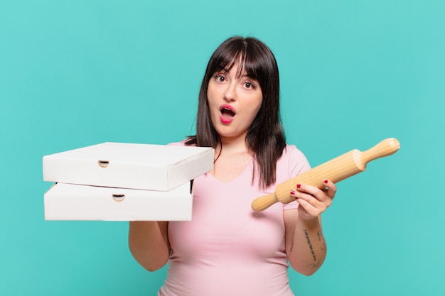 Young pretty curvy woman scared expression and holding a pizza