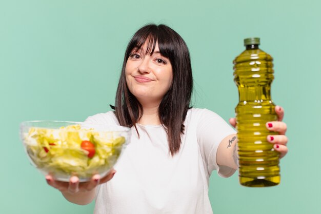 Foto giovane donna abbastanza formosa con l'espressione felice e con in mano un'insalata