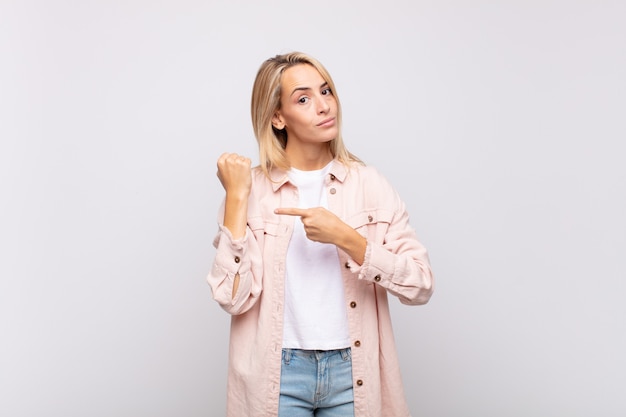 young pretty disappointed woman showing imaginary hour in her wrist