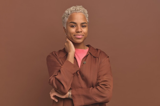 Young pretty ethnic african american woman slightly smiling keeps hand on neck