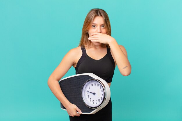 Young pretty fitness woman covering mouth with hands with a shocked