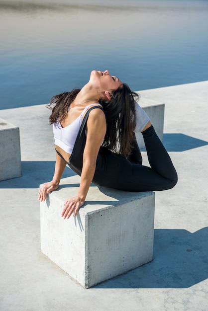 Giovane donna graziosa di forma fisica che fa le posizioni di yoga, streching nella natura. uno stile di vita sano