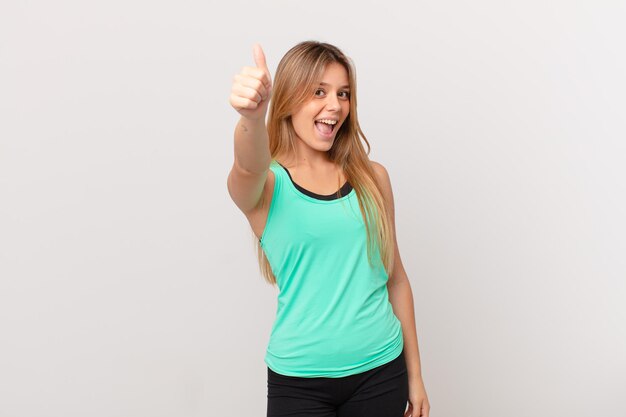 Young pretty fitness woman feeling proud,smiling positively with thumbs up