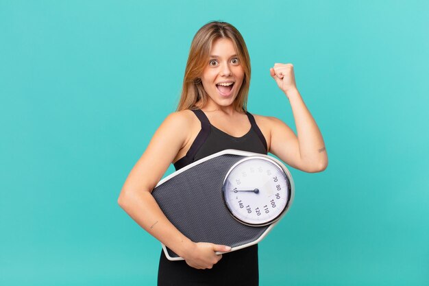 Giovane donna graziosa di forma fisica che si sente scioccata e ride e celebra il successo