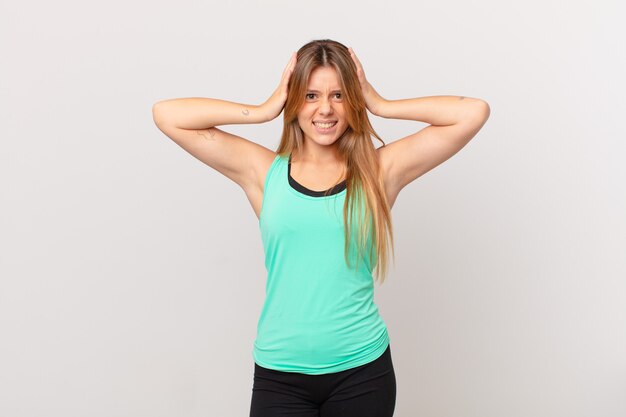 Young pretty fitness woman feeling stressed, anxious or scared, with hands on head