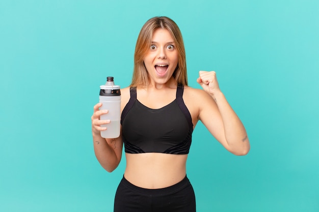 Young pretty fitness woman shouting surprised