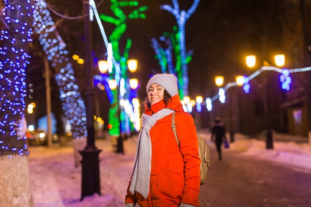 Giovane ragazza abbastanza divertente che si diverte all'aperto nella città di natale invernale e nel concetto di vacanze invernali