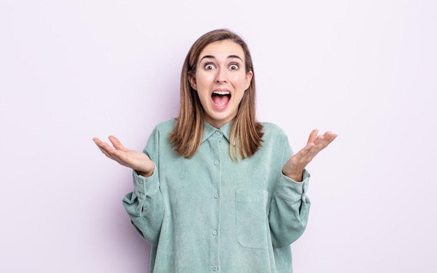 Young pretty girl feeling happy, excited, surprised or shocked, smiling and astonished at something unbelievable