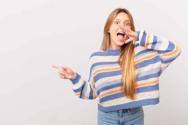 Young pretty girl feeling happy,giving a big shout out with hands next to mouth