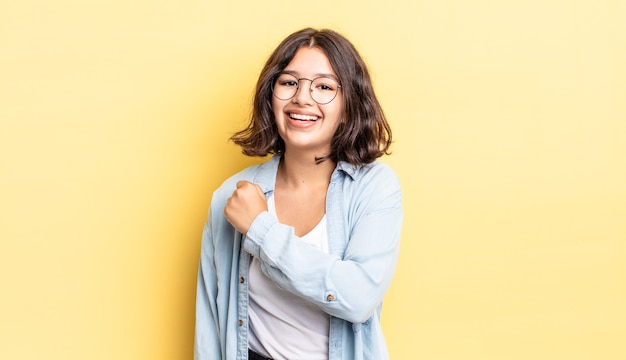 Giovane ragazza carina che si sente felice, positiva e di successo, motivata quando affronta una sfida o celebra buoni risultati