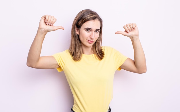 Young pretty girl feeling proud, arrogant and confident, looking satisfied and successful, pointing to self