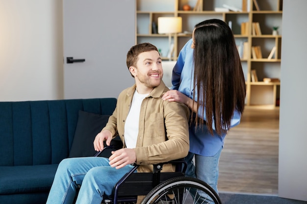 A young pretty girl helps her friend who is confined to a wheelchair