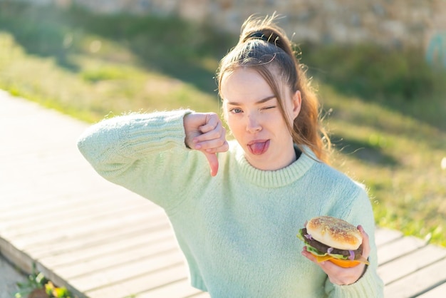 写真 屋外でハンバーガーを保持している若いきれいな女の子