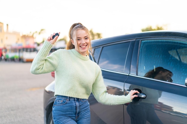 屋外で車のキーを保持している若いきれいな女の子