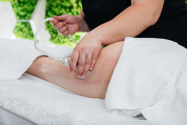 A young pretty girl is enjoying a professional vacuum massage at the Spa. Body care. Beauty salon.