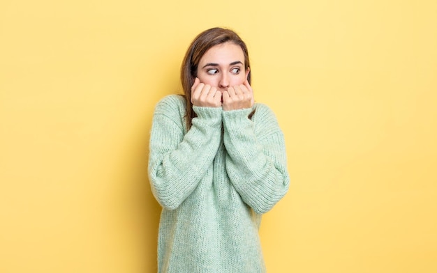 Young pretty girl looking worried anxious stressed and afraid biting fingernails and looking to lateral copy space