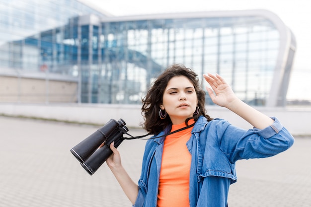 La giovane ragazza graziosa distoglie lo sguardo con un binocolo in mano.