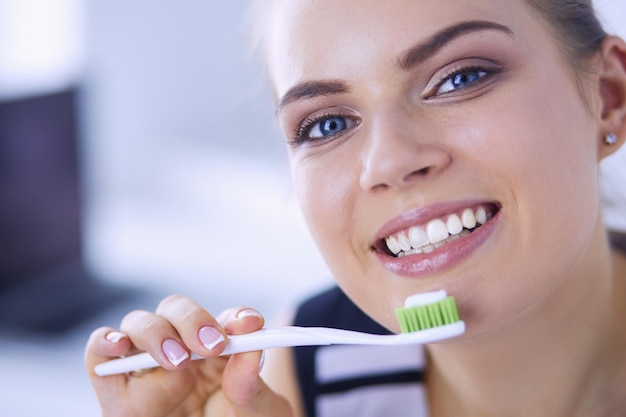 Молодая красивая девушка поддерживает гигиену полости рта зубной щеткой