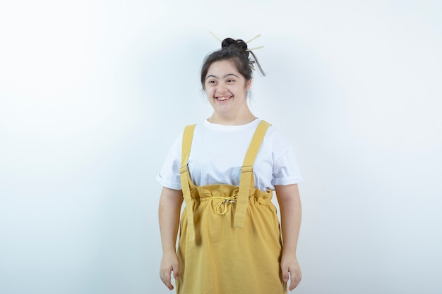 Young pretty girl model standing and smiling widely against white wall .