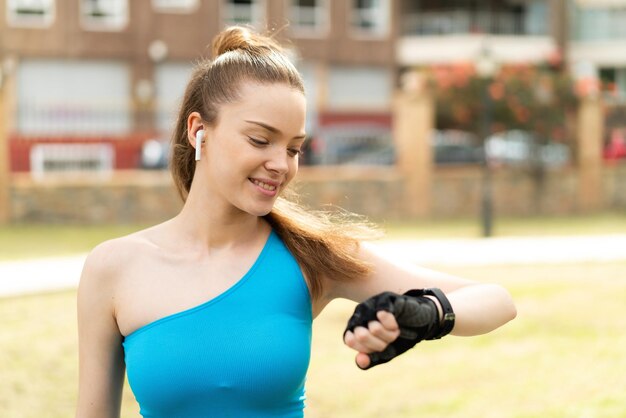 Foto giovane bella ragazza all'aperto che fa sport con orologio sportivo