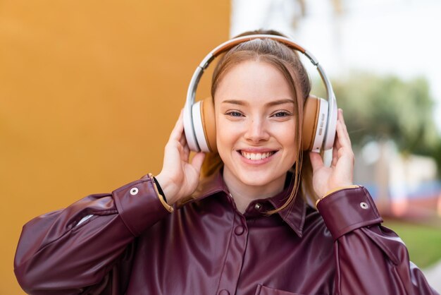 Young pretty girl at outdoors listening music