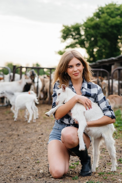 A young pretty girl poses on a ranch with goats and other\
animals. agriculture, livestock breeding.